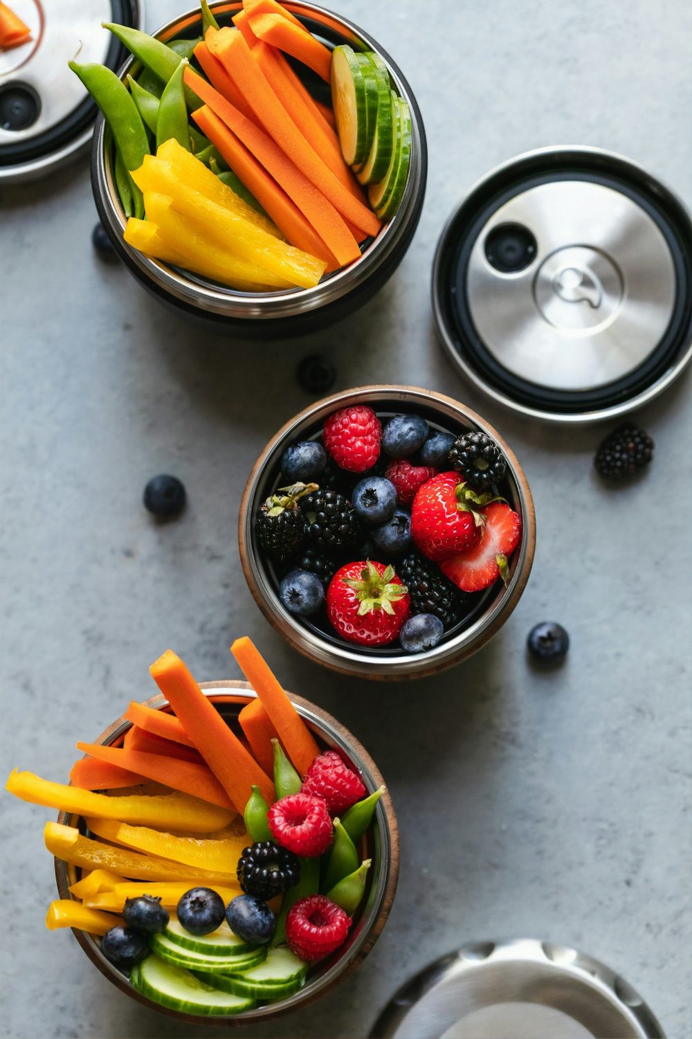 Bowls of fresh fruit and vegetable sticks as healthy snacks